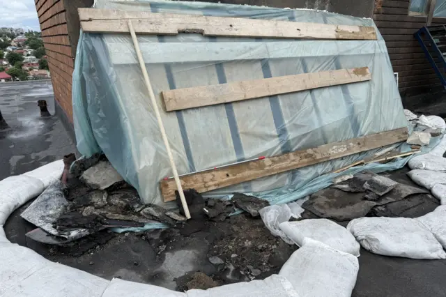 Місце удару дрона по даху житлового будинку, покритому дерев'яними панелями та синім пластиком.