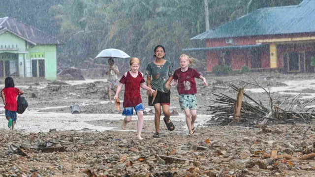 Warga korban bencana banjir dan tanah longsor berlarian untuk mengambil bantuan di Kelurahan Huta Nabolon, Kecamatan Tukka,Tapanuli Tengah, Sumatra Utara, Minggu (7/12/2025). Warga di empat desa wilayah tersebut hanya bisa mengambil bantuan di saat aliran air akibat banjir dan tanah longsor surut. 