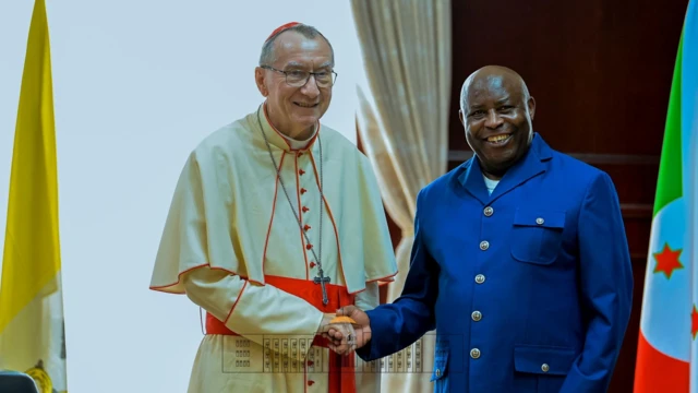 Cardinal Pietro Palorin (i bubamfu) na Perezida w'Uburundi Evariste Ndayishimiye bahanye ikiganza bifotoza, Bujumbura ku wa 12 Myandagaro 2025