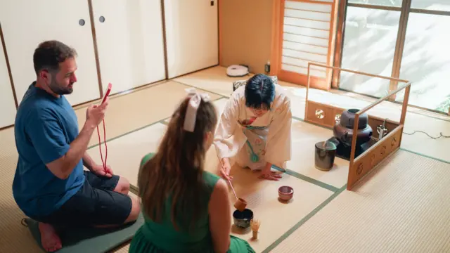 Seorang ahli upacara minum teh Jepang mengajari turis cara membuat teh matcha tradisional Jepang.