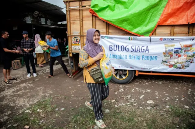 Orang-orang membawa kantong beras dari program Stabilisasi Pengendalian Harga Pangan pemerintah di Bekasi, Jawa Barat, pada 27 Februari 2024.
