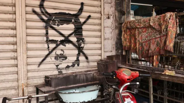 Перечеркнутое граффити свергнутого президента Сирии Башара Асада рядом с магазином в Дамаске