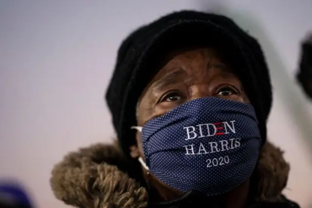Un homme portant un masque sur lequel on peut lire "Biden Harris 2020".
