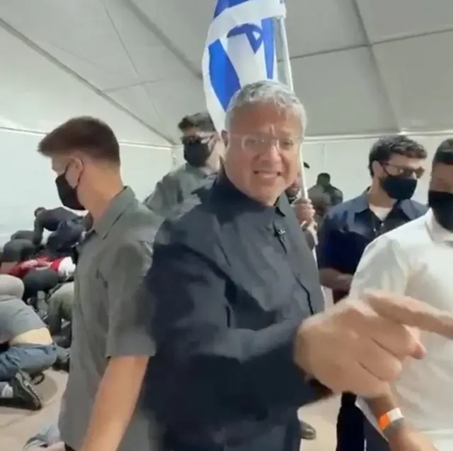 Menteri Keamanan Nasional Israel memberi isyarat di depan bendera Israel saat mengunjungi sebuah fasilitas di pelabuhan Ashdod, Israel, tempat para aktivis pro-Palestina dari flotila menuju Gaza ditahan (20 Mei 2026).