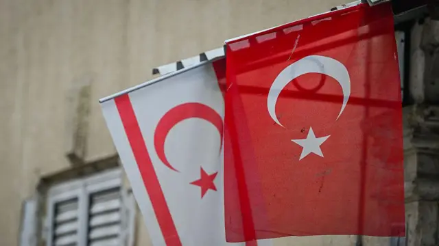 Bir sokakta Türkiye ve Kıbrıs Türk tarafı bayrağı yan yana sallanıyor.