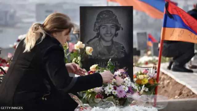 امرأة تضع زهوراً على قبر أحد الجنود