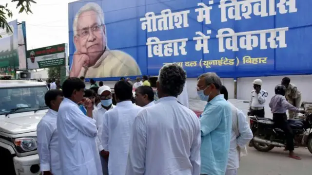 नीतीश कुमार के बैनर के सामने खड़े जेडीयू समर्थक