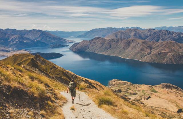 Un hombre caminando entre las montañas de Nueva Zelanda hasta un lago