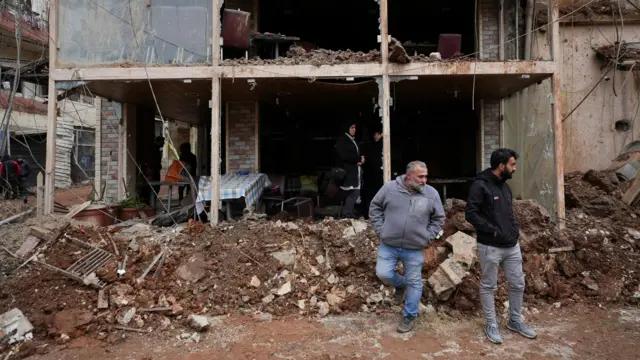 İki adam enkaza dönmüş bir binanın kalıntıları arasından çıkıyor.