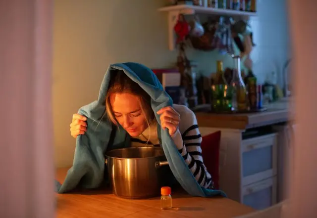 এক নারী মাথার ওপর দিয়ে তোয়ালে টেনে নীচে গাড়ির দিকে মুখ ঝুঁকিয়ে আছেন। পাশে একটি ছোট বোতল