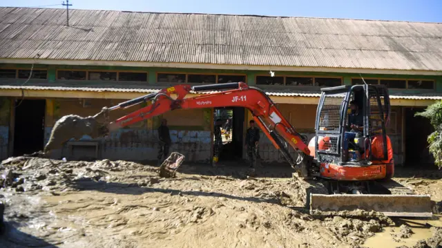 Petugas mengoperasikan alat berat untuk membersihkan lokasi dari endapan lumpur di SD Negeri 1 Kuala Simpang, Kabupaten Aceh Tamiang, Aceh, Minggu (25/1/2026). 