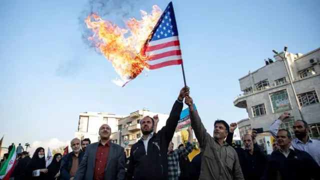 Pessoas queimando uma bandeira dos Estados Unidos