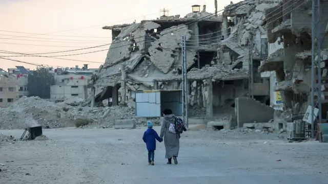 17 Kasım 2025'te, Suriye'nin güneyindeki savaşın izlerini taşıyan Darayya bölgesinde, çocuklar aileleri eşliğinde okula gidiyor.