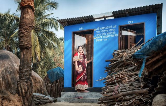 Une femme se tient devant de nouvelles installations sanitaires dans le district de Satkhira, au Bangladesh.