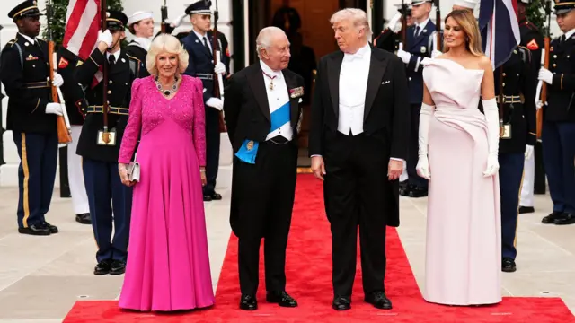 Краљ и краљица, Трамп и Меланија испред улаза у Белу кућу, окружени војницима, гардистима и заставама, на црвеном тепиху.