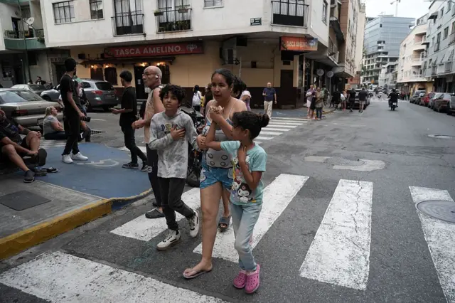 Una mujer camina por la calle con su hija e hijo cogidos de la mano, asustados después del terremoto.