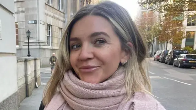 Mujer con una bufanda rosa camina por las calles de Londres