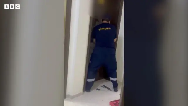 صورة حصلت عليها بي بي سي توضح أحد رجال الدفاع المدني بصحبة الشرطة، وهو يفتح بالقوة باب إحدى الشقق السكنية في مكة