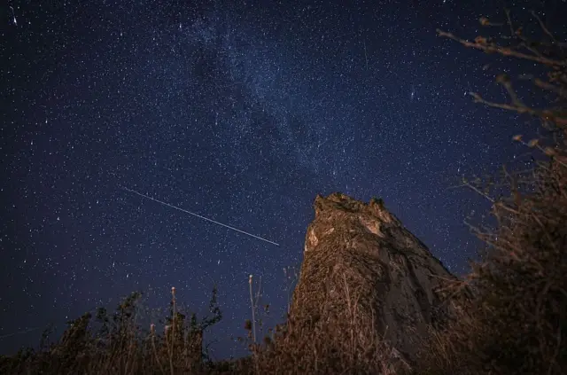 Kayan bir yıldız lacıvert ve karanlık gökyüzünde fotoğraflanmış.