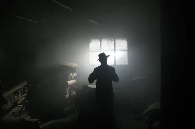 Silhouette of a man wearing hat in a warehouse