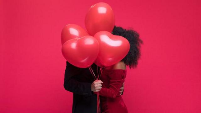 Casal escondido por balões de coração
