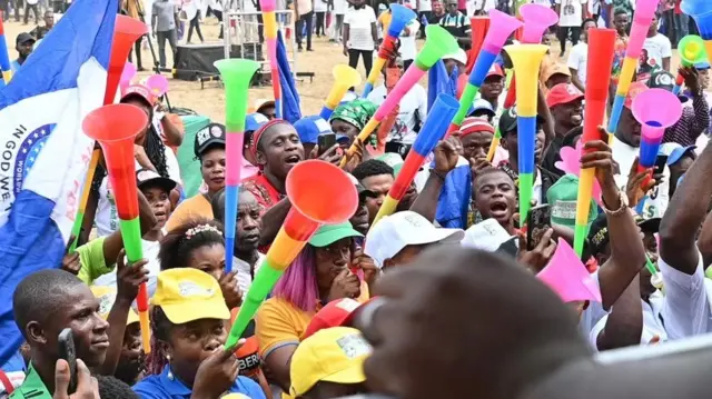 Une foule souflant sur des vuvuzelas.