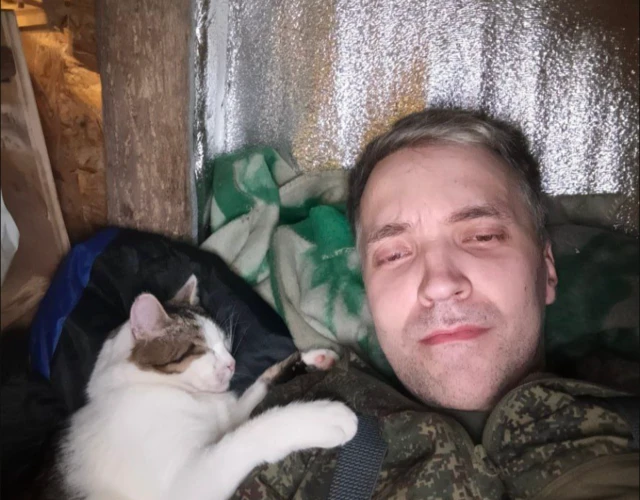 Человек в военной форме с котом, дремлющим у него на плече