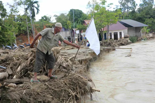 Warga memasangkan bendera putih di depan rumahnya yang rusak pasca bencana hidrometeorologi di Desa Lawet, Kecamatan Pante Ceureumen, Aceh Barat, Aceh, Rabu (17/12/2025). Pengibaran bendera putih tersebut sebagai bentuk protes masyarakat terhadap pemerintah pusat untuk menetapkan bencana di Sumatera menjadi status bencana nasional sehingga bantuan negara-negara internasional dapat masuk untuk mempercepat penangganan bencana secara maksimal.