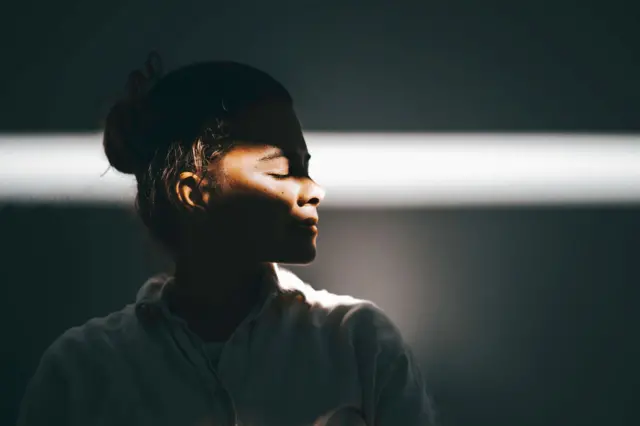 Mulher de perfil, com feixe de luz batendo na altura dos olhos