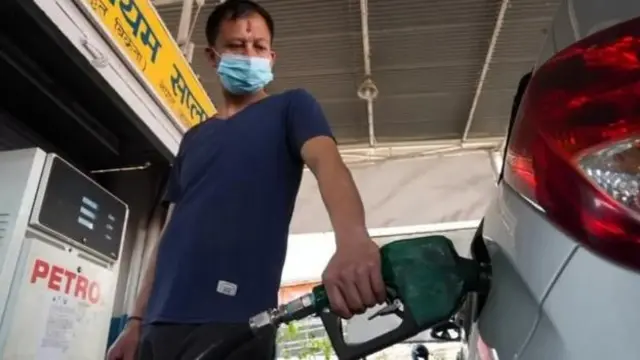 एक पेट्रोल पम्पको दृश्य। एक जना निलो रङ्गको भेस्ट लगाएका व्यक्ति कारमा पेट्रोल हाल्दै छन्