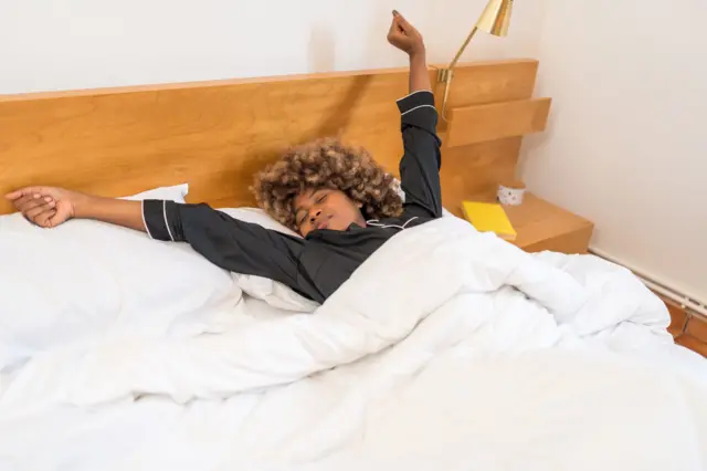 Femme qui s'étire dans son lit