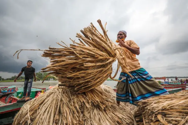 নৌকায় পাটের বেল তুলছে শ্রমিকরা