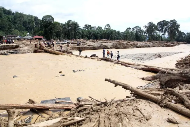 Warga berjalan melintasi sungai dengan jembatan darurat di Desa Aek Garoga, Kecamatan Batang Toru, Kabupaten Tapanuli Selatan, Sumatera Utara, Sabtu (29/11/2025).
