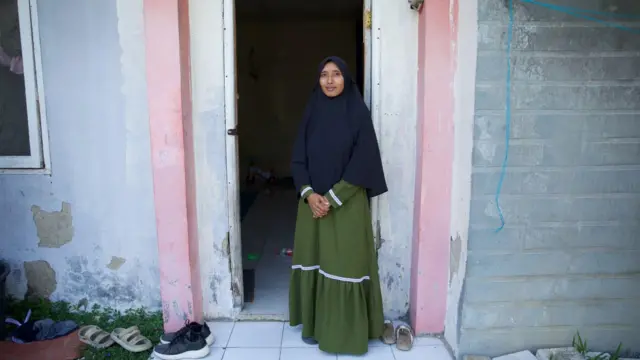 Hari Fitriani berdiri di depan rumahnya. Ia sudah tinggal di sana sejak 2018.