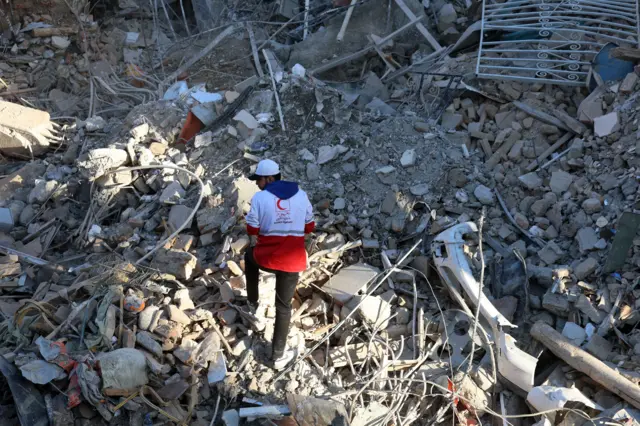 Um funcionário da Cruz Vermelha iraniana vasculha os escombros da sinagoga Khorasaniha, destruída em Teerã, Irã, em 7 de abril de 2026. Uma operação militar conjunta israelense e americana continua a atingir vários locais no Irã desde as primeiras horas de 28 de fevereiro de 2026.