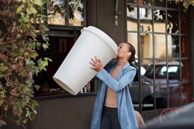 Mulher com uma xícara gigante com café