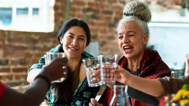 Жіінки за столом чокаються склянками