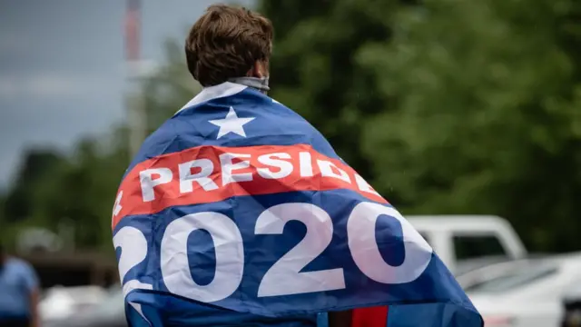 JOven que apoya a Biden con una bandera en la espalda