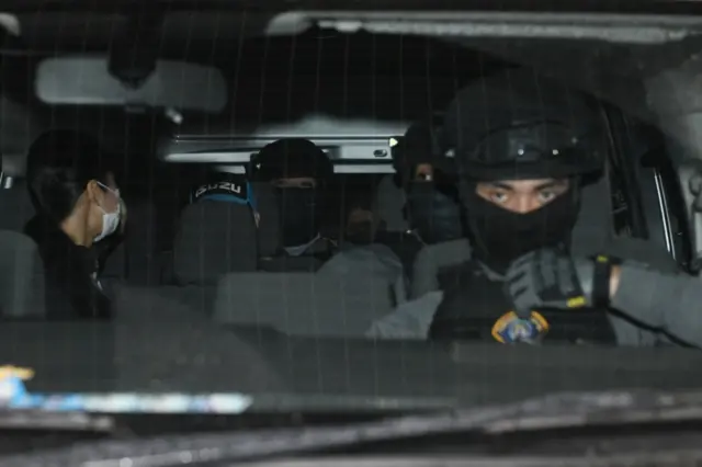 ผู้กำกับโจ้ (สวมหมวกสีฟ้า) นั่งรถควบคุมผู้ต้องหาไป จ. นครสวรรค์