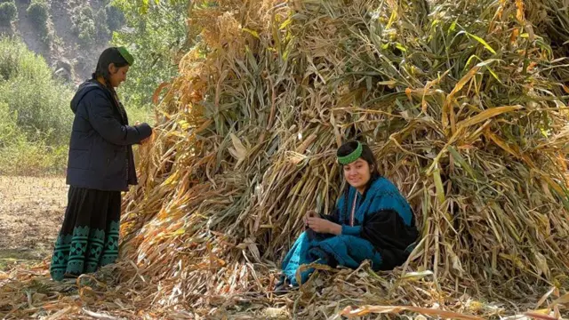 Kalash women by a large pile of foliage