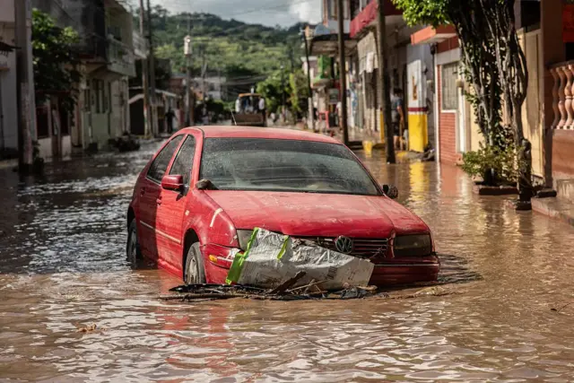 Un automóvil rojo en una calle inundada