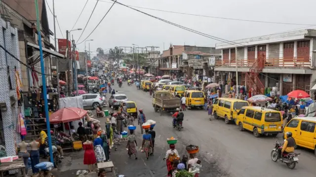 A busy street in Goma filled with people and yellow vans.