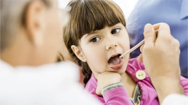 Niña mostrándole la lengua al médico.