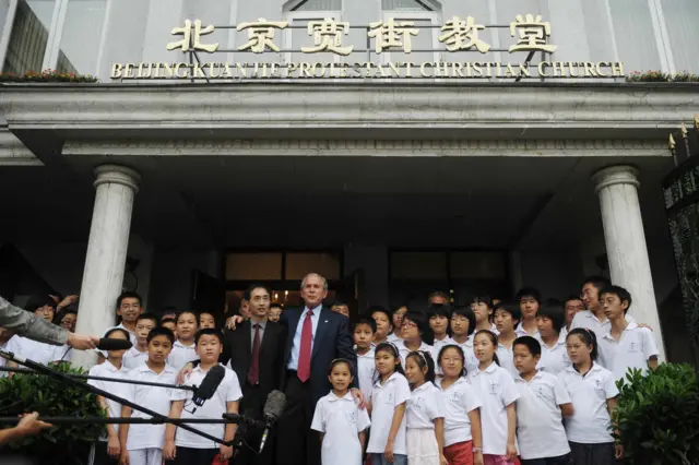 北京宽街教堂门外乔治·布什（中）与信众合影，包括一群身穿白衣的儿童（10/8/2008）