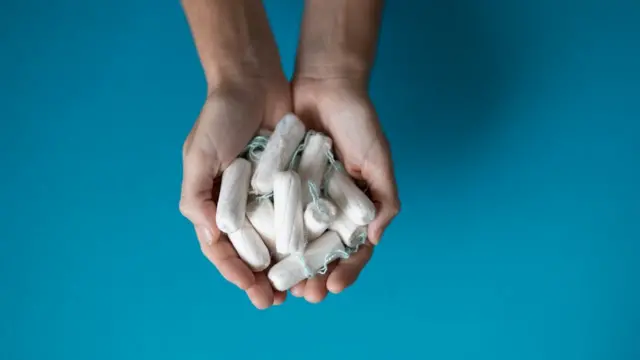 Mão segurando vários absorventes internos