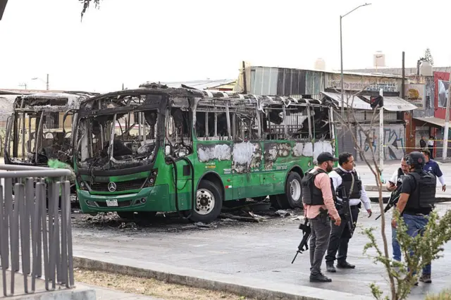  Anggota keamanan berbicara di samping bus yang terbakar pada 22 Februari 2026 di Zapopan, Meksiko. Blokade jalan dan pembakaran kendaraan telah dilaporkan di beberapa bagian Meksiko sejak pagi hari. Sekretariat Pertahanan Nasional Meksiko telah mengkonfirmasi bahwa selama operasi keamanan di Tapalpa, Jalisco, Nemesio Oseguera Cervantes, yang dikenal sebagai 'El Mencho', pemimpin Kartel Generasi Baru Jalisco, tewas, bersama dengan empat anggota lainnya. Tiga tentara Meksiko terluka selama operasi tersebut.