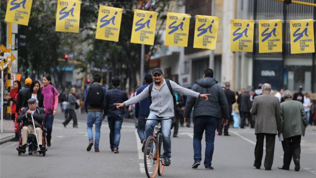 Un hombre en monociclo bajo carteles a favor del "sí" en Colombia.