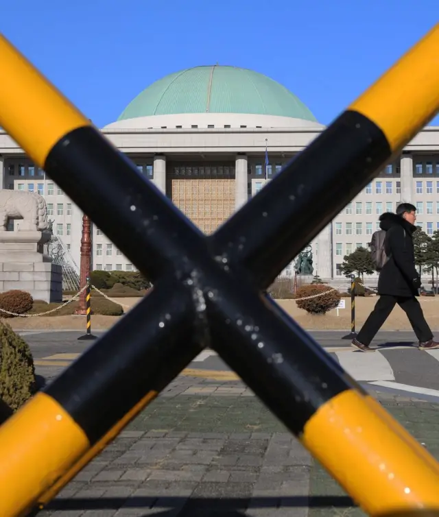 서울 여의도 국회 정문 바리케이드 앞으로 시민이 걸어가고 있는 모습