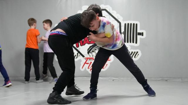 Daniel lutando com outra criança em uma aula de luta