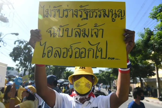 ผู้ชุมนุมกลุ่ม "ไทยภักดี" ถือป้ายที่เขียนข้อความคัดค้านร่างรัฐธรรมนูญ "ฉบับไอลอว์"